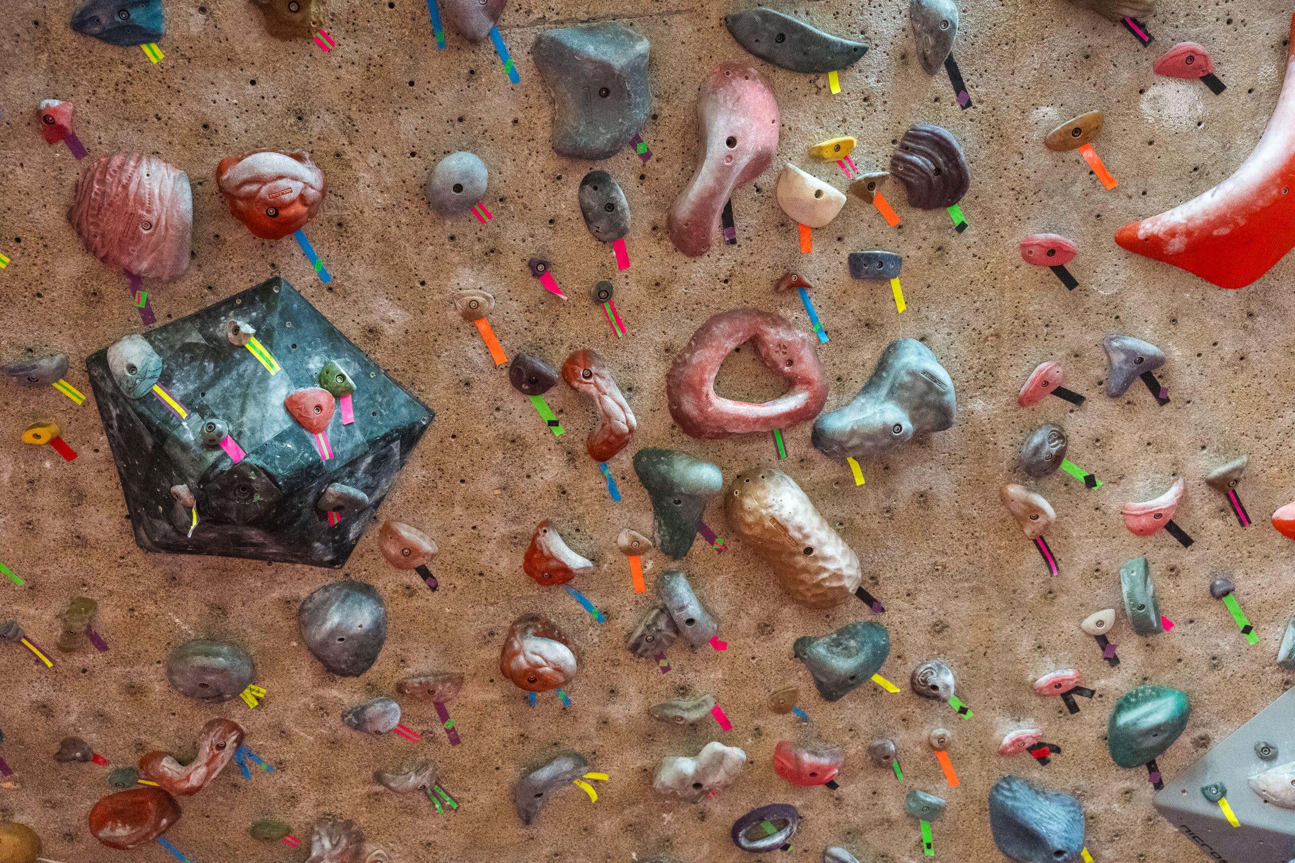 an indoor bouldering gym with rock climbing hand holds scattered around.